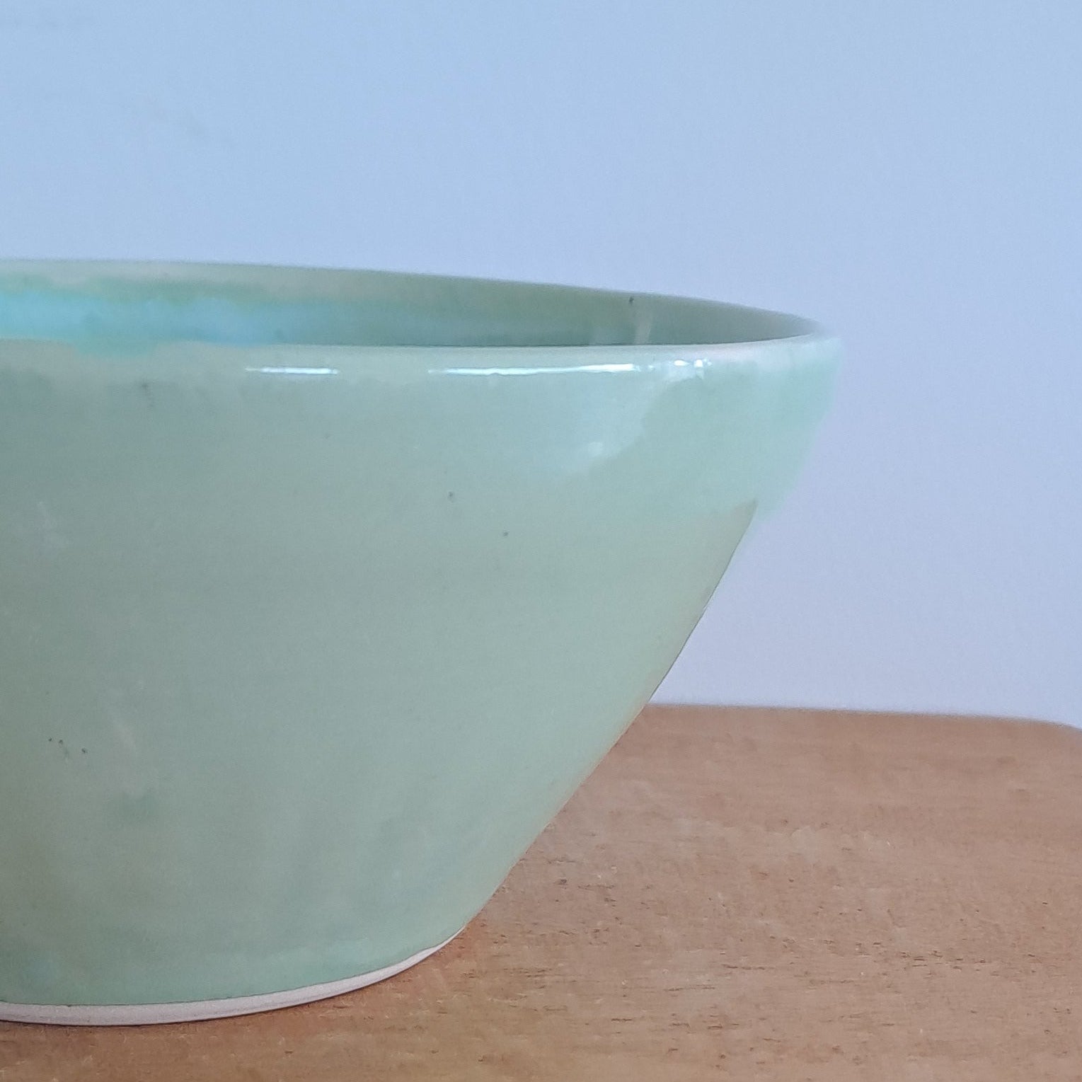 Light green bowl on a wooden surface with a blurred background