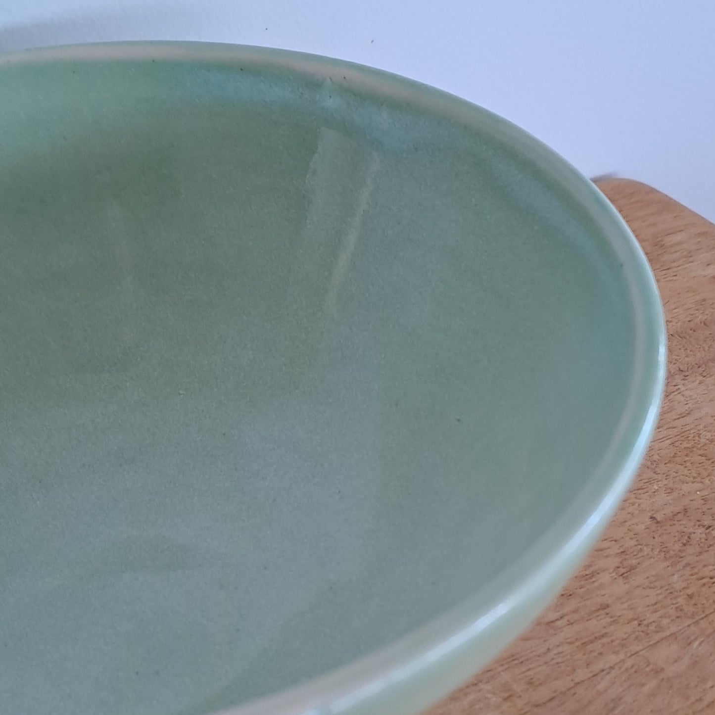 Light green ceramic bowl on a wooden surface