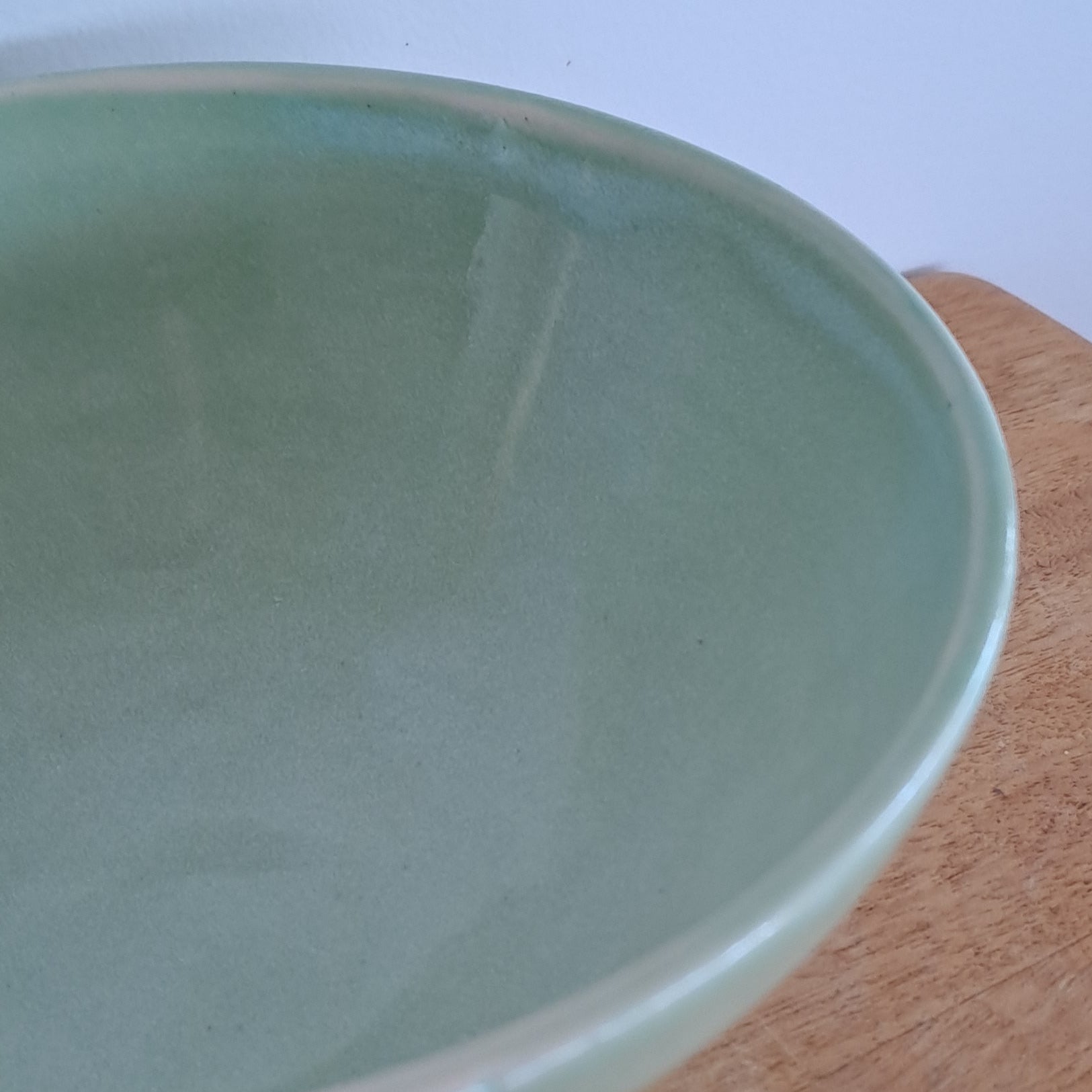 Light green ceramic bowl on a wooden surface