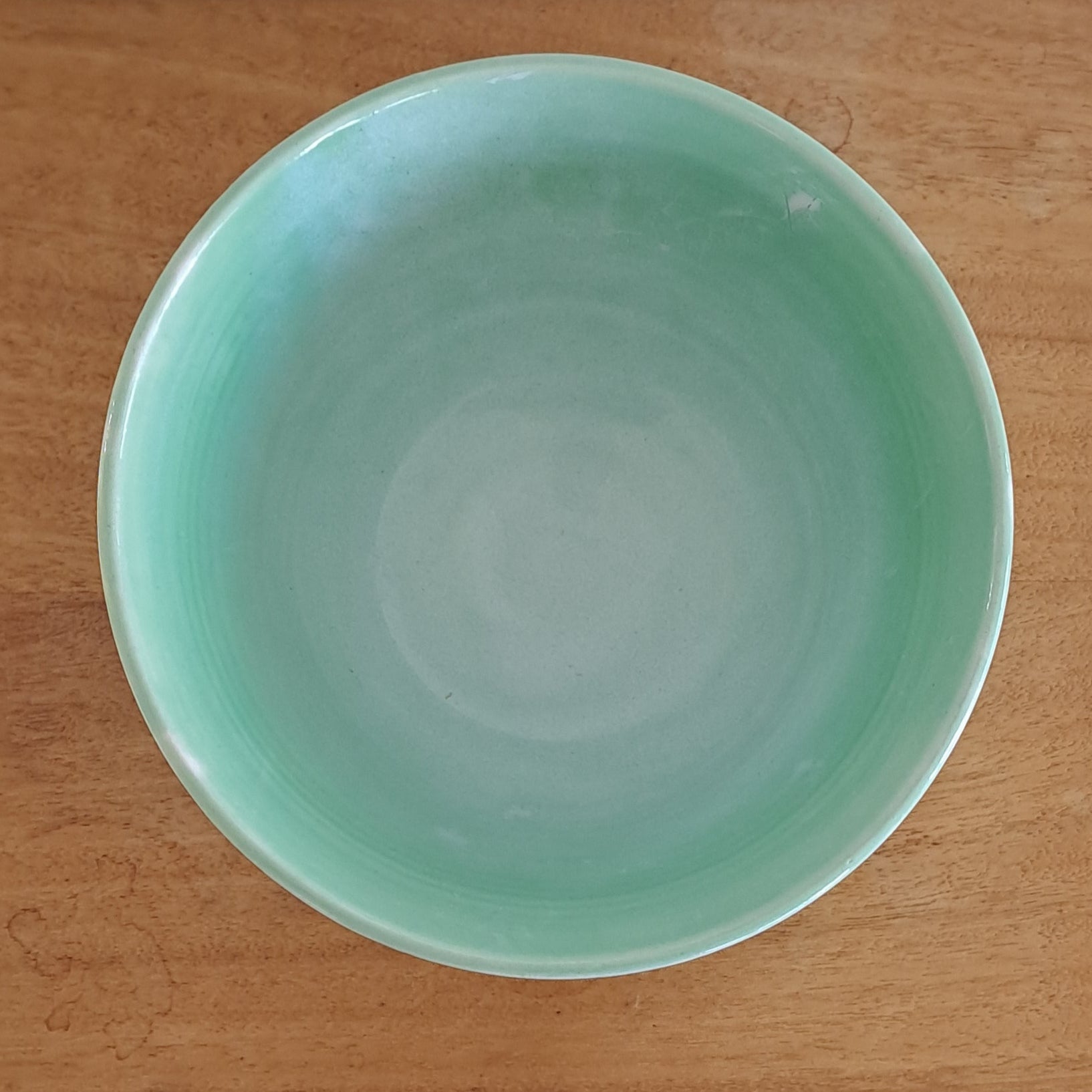 Green ceramic bowl on a wooden surface
