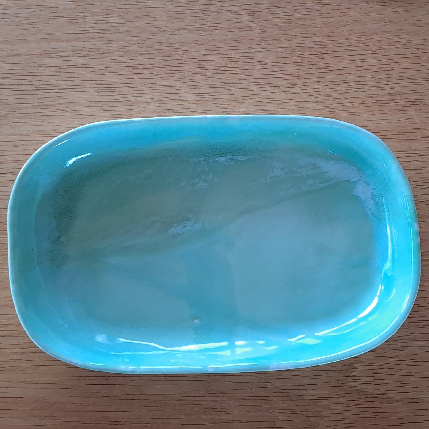Green ceramic platter on a wooden surface with a white background