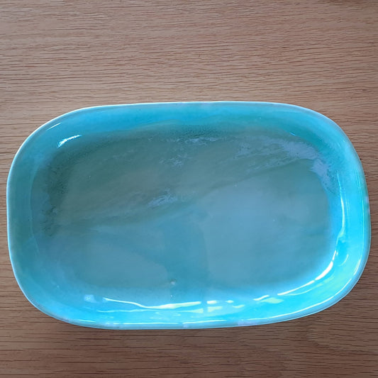 Green ceramic platter on a wooden surface with a white background