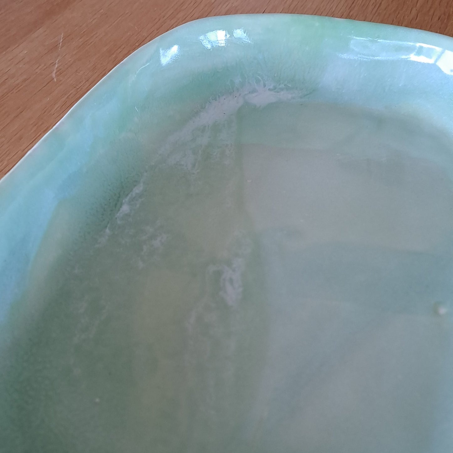 Green ceramic platter  on a wooden surface with a white background