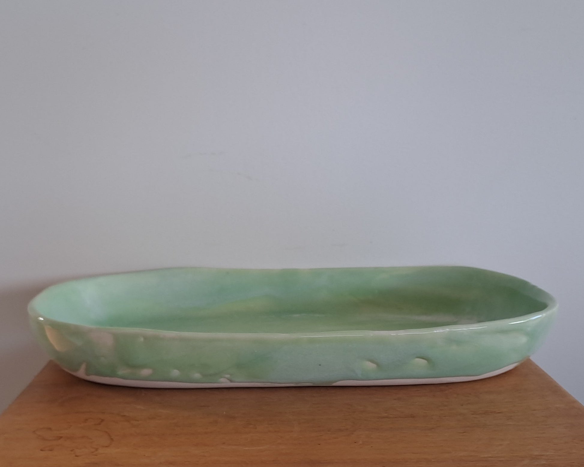 Green ceramic dish on a wooden surface with a plain background