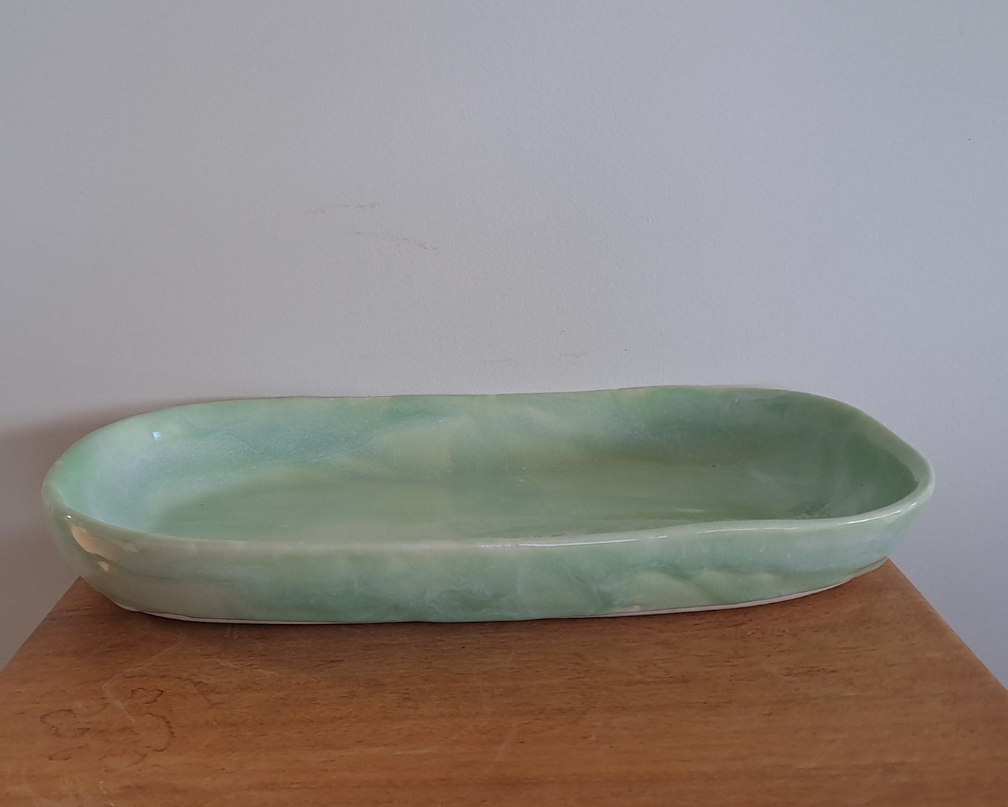 Green ceramic dish on a wooden surface with a white background