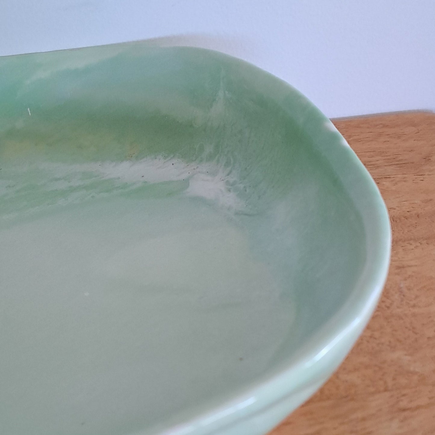 Light green ceramic dish on a wooden surface with a blurred background