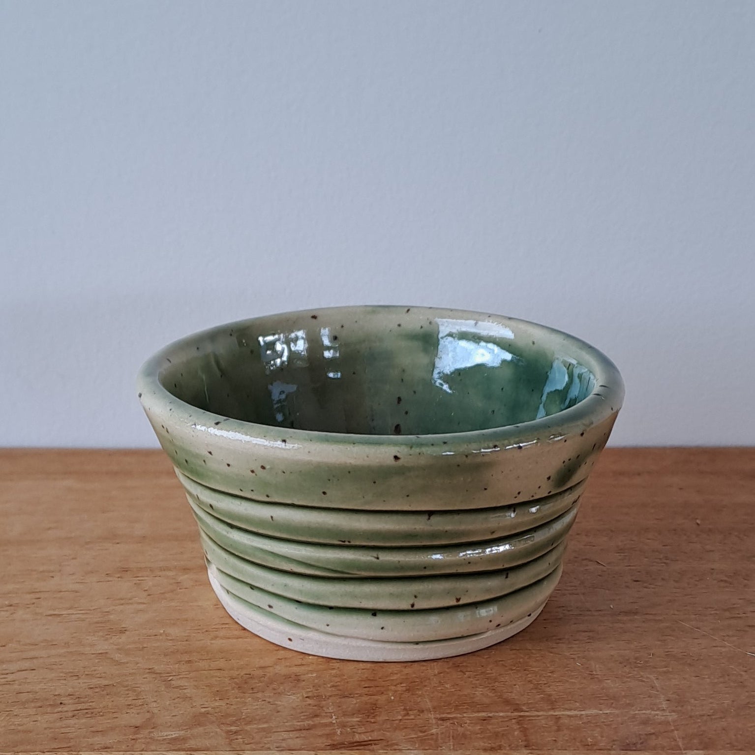 Small ceramic container on a wooden surface with a white background