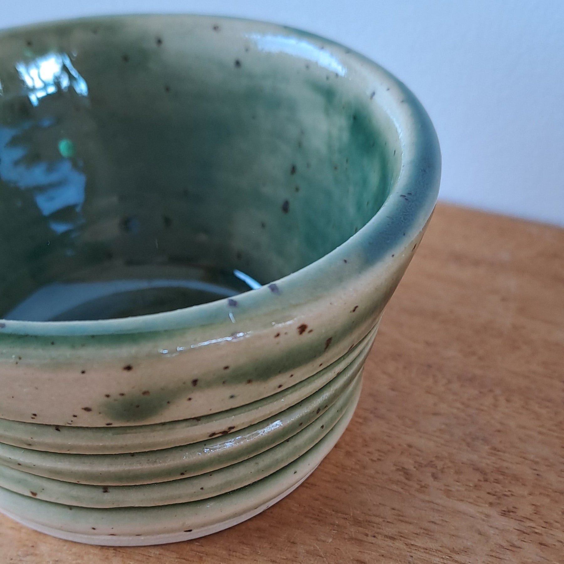 Ceramic bowl with green interior on a wooden surface