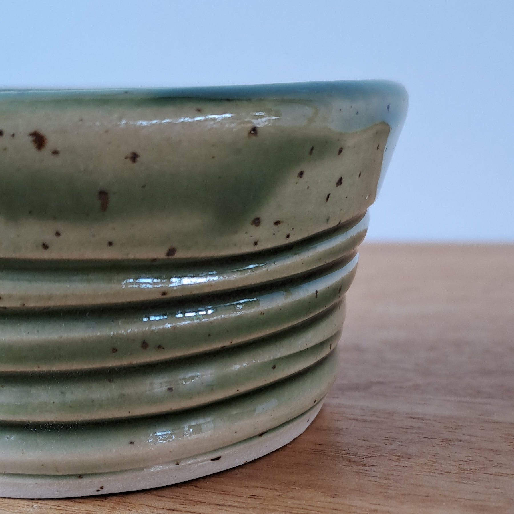 Close-up of a ceramic bowl with a textured surface against a light blue background