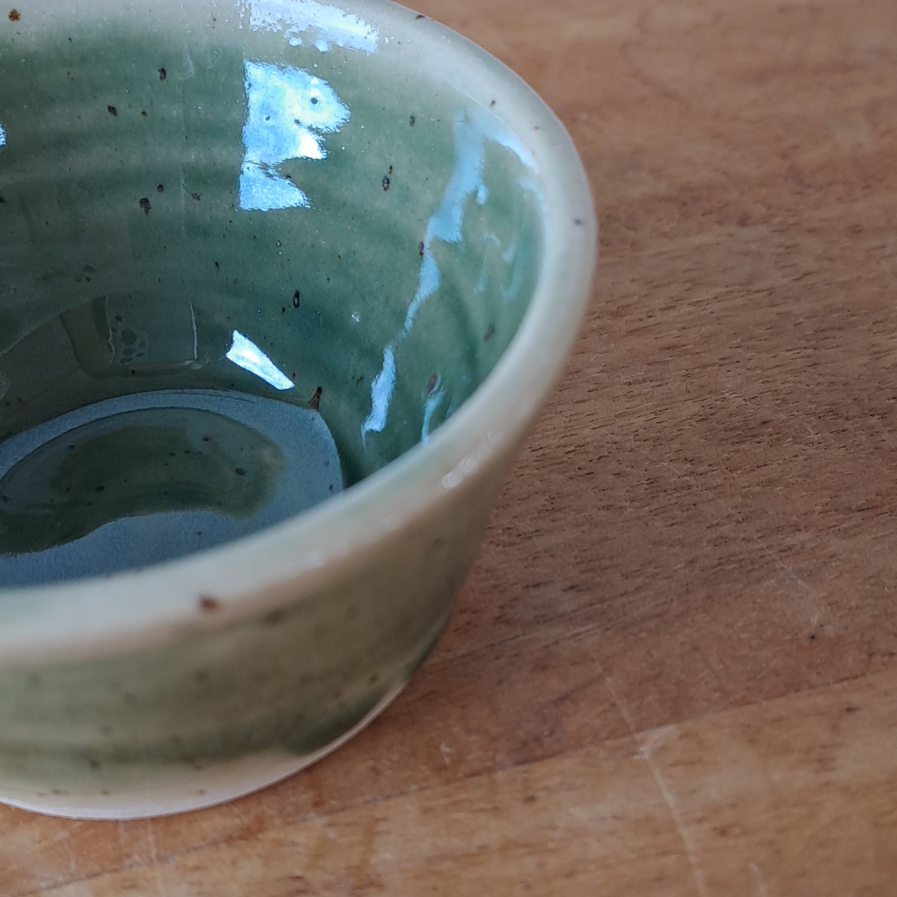 Green ceramic bowl on a wooden surface